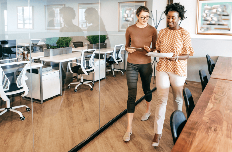 Two female employees walking and talking in their office