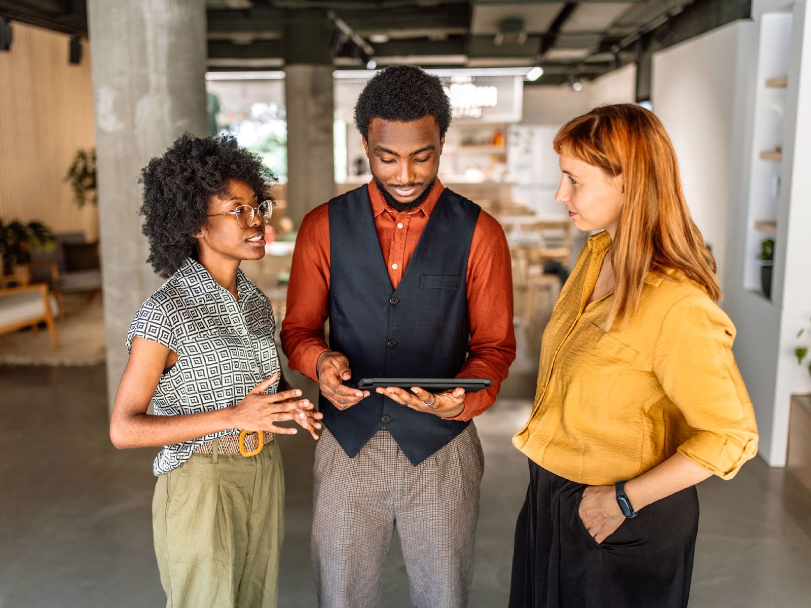 three employees looking at a tablet discussing employee engagement trends