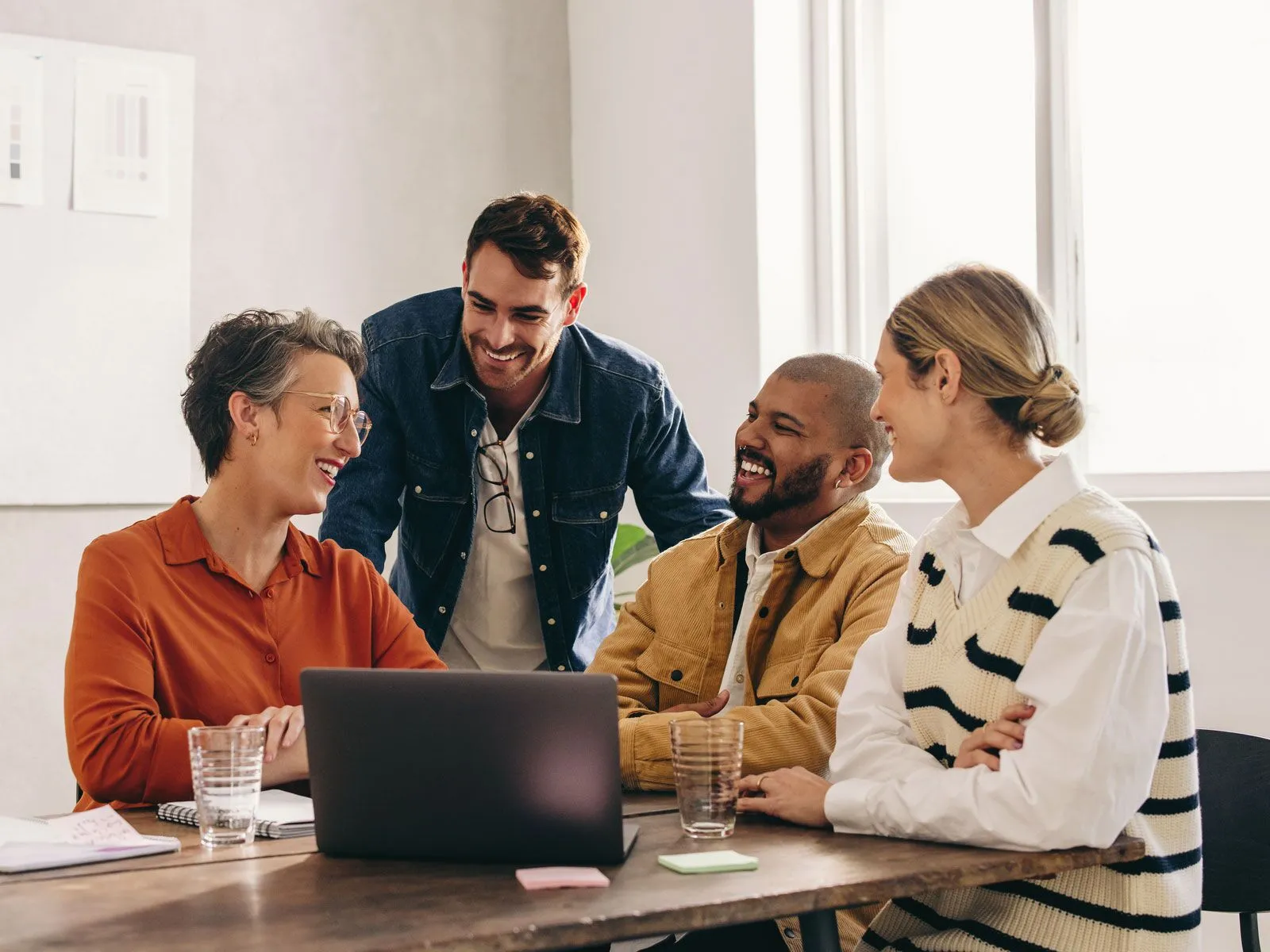 group of employees sitting around a laptop smiling