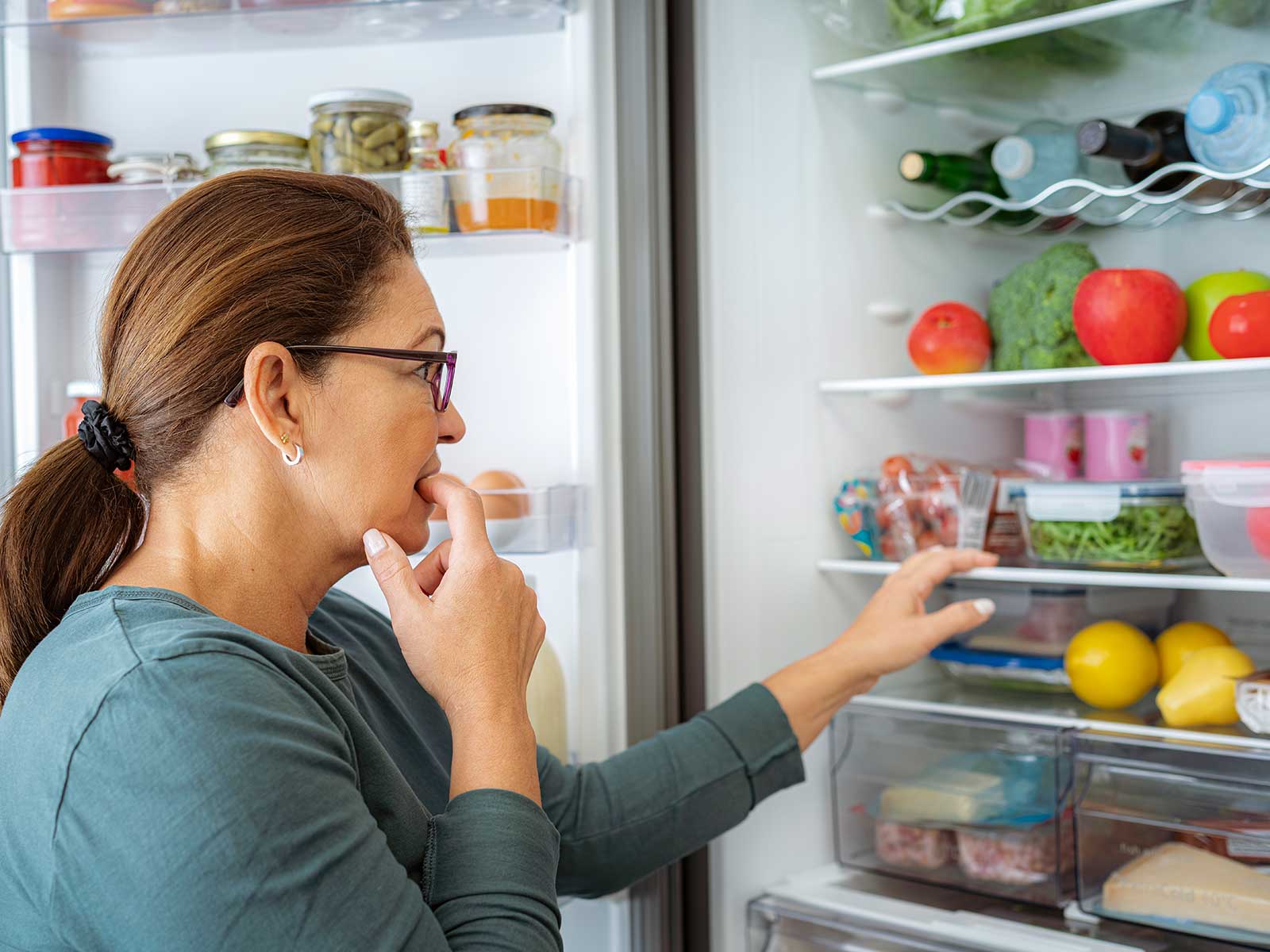 Woman thinking about what to eat from her fridge