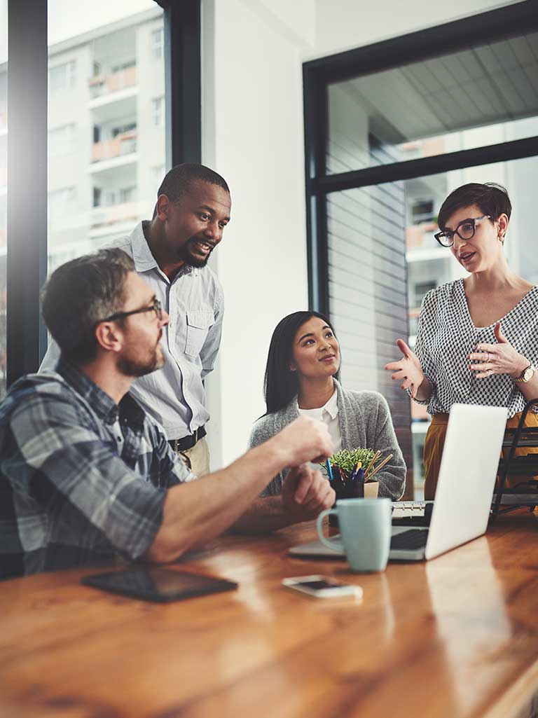 employees discussing work at a table with a computer