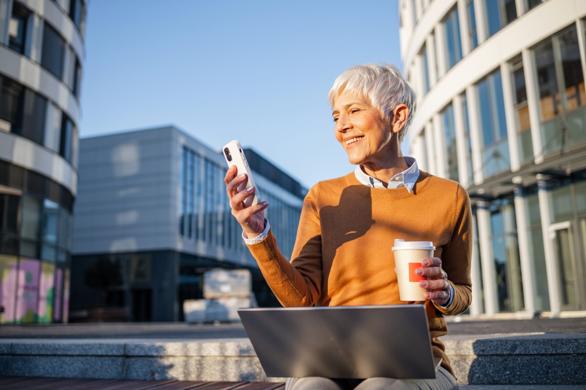 woman practicing work-life balance while outside the office with her laptop and coffee