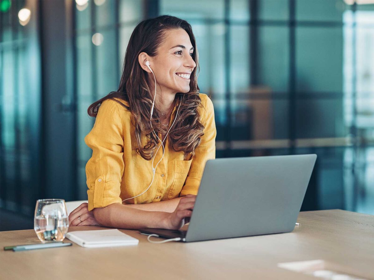 employee smiling after responding to employee attrition and turnover survey questions on her laptop