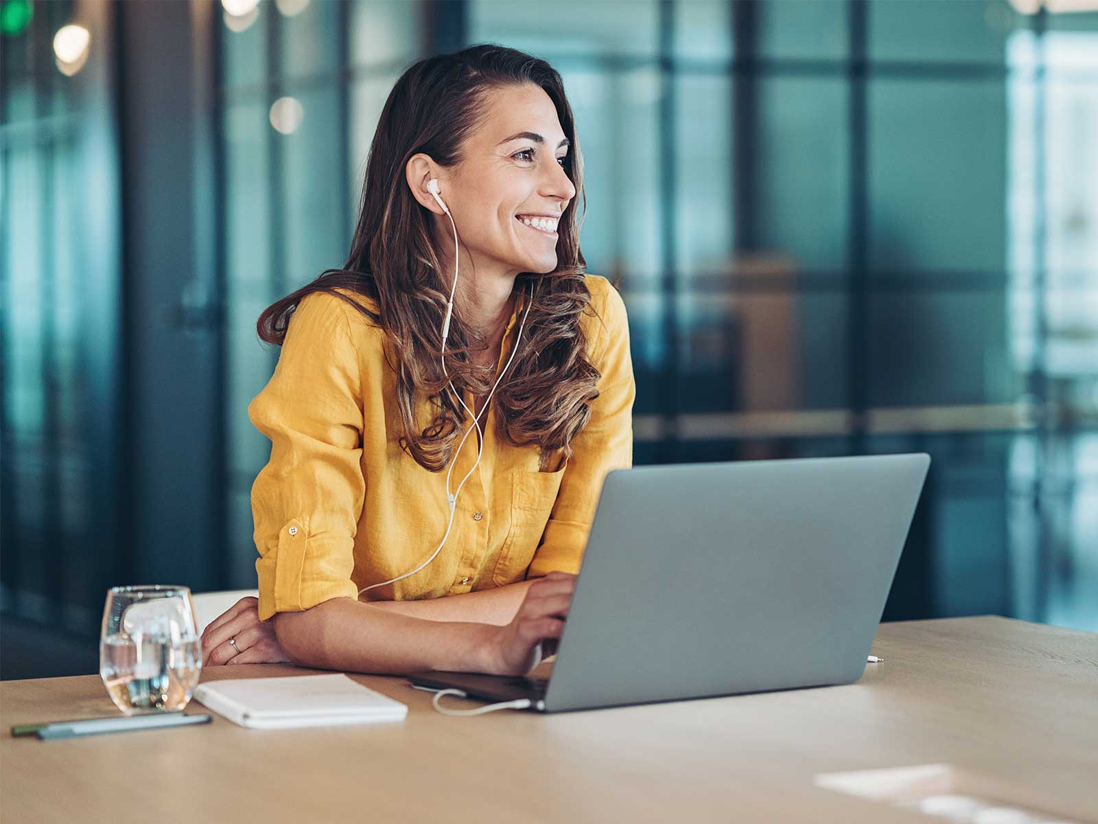 employee smiling after responding to employee attrition and turnover survey questions on her laptop