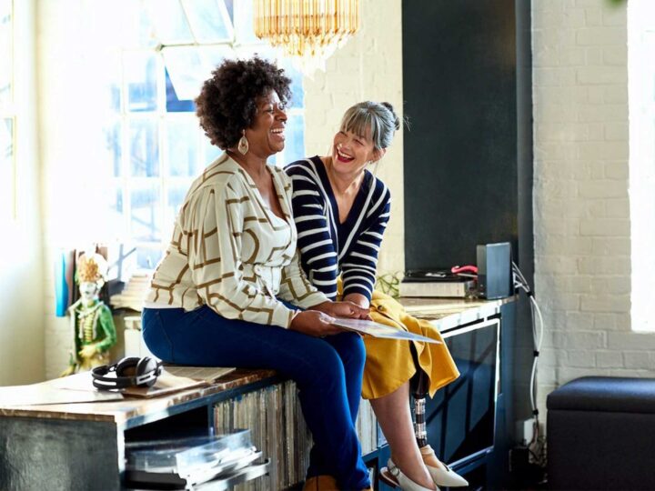 2 women smiling and laughing discussing corporate wellness program statistics