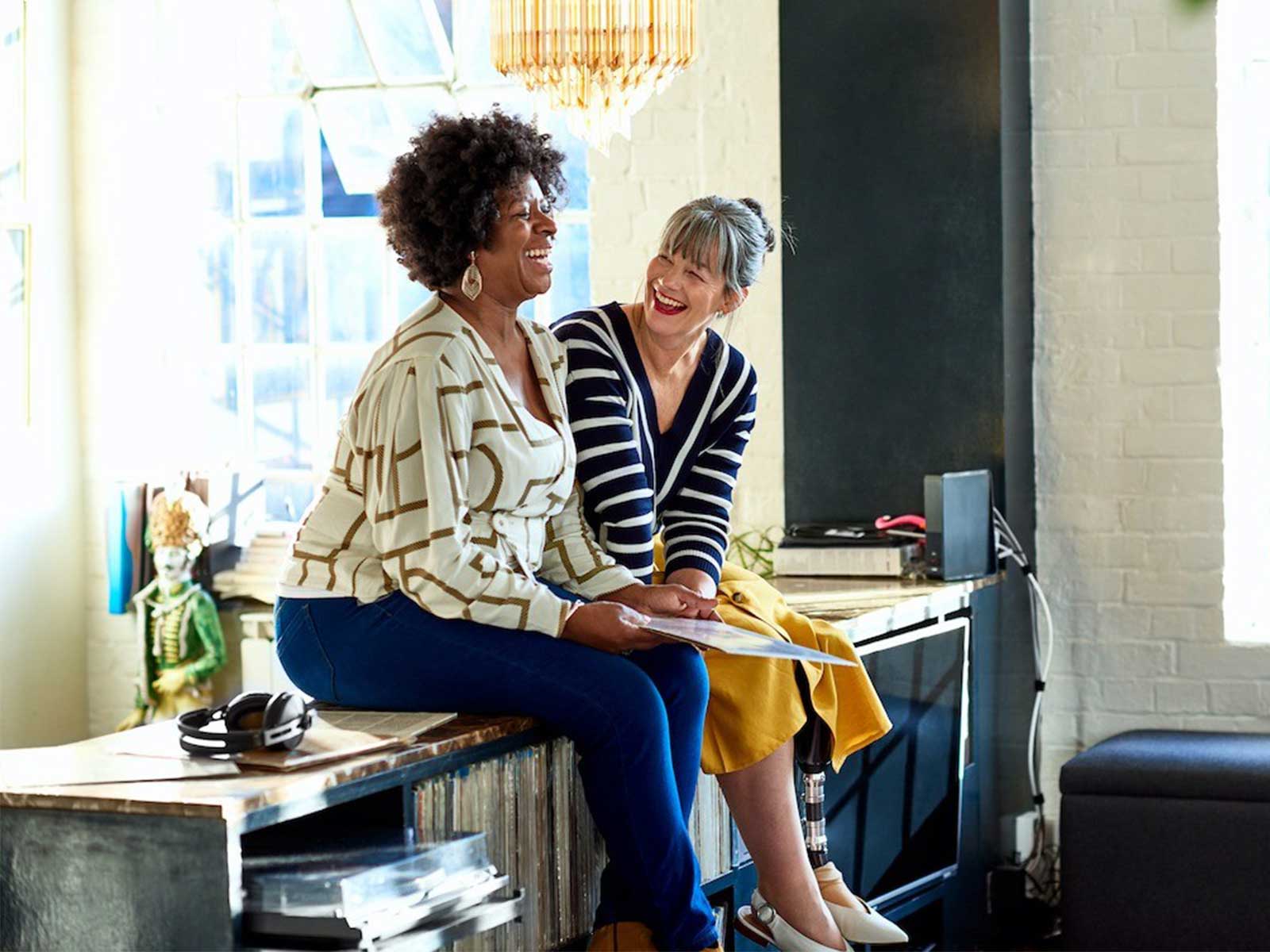2 women smiling and laughing discussing corporate wellness program statistics