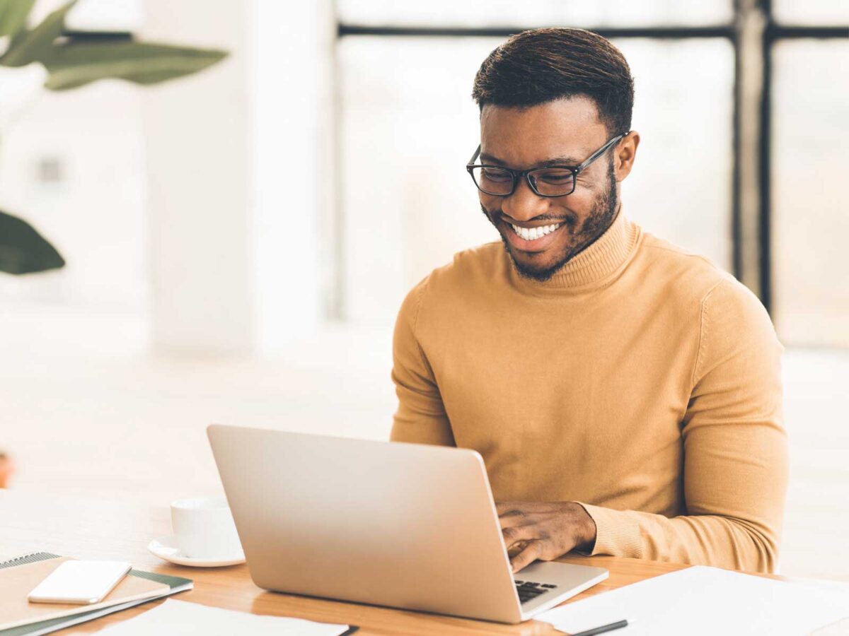 man smiling and working on his laptop