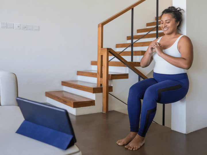 Woman doing an in-home workout, squatting against a wall.