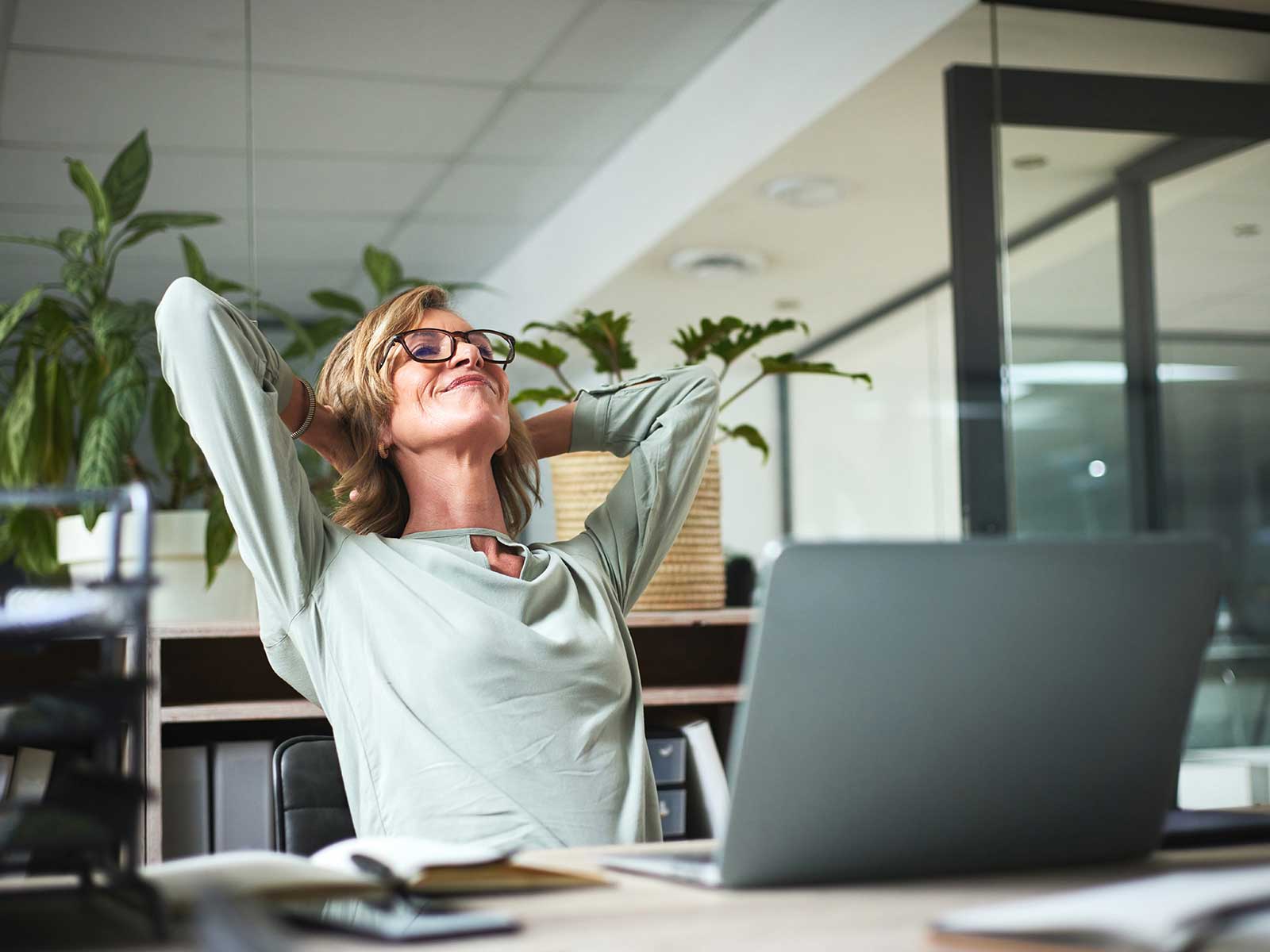 Woman relaxing at her desk because here company prioritizes mental health in the workplace