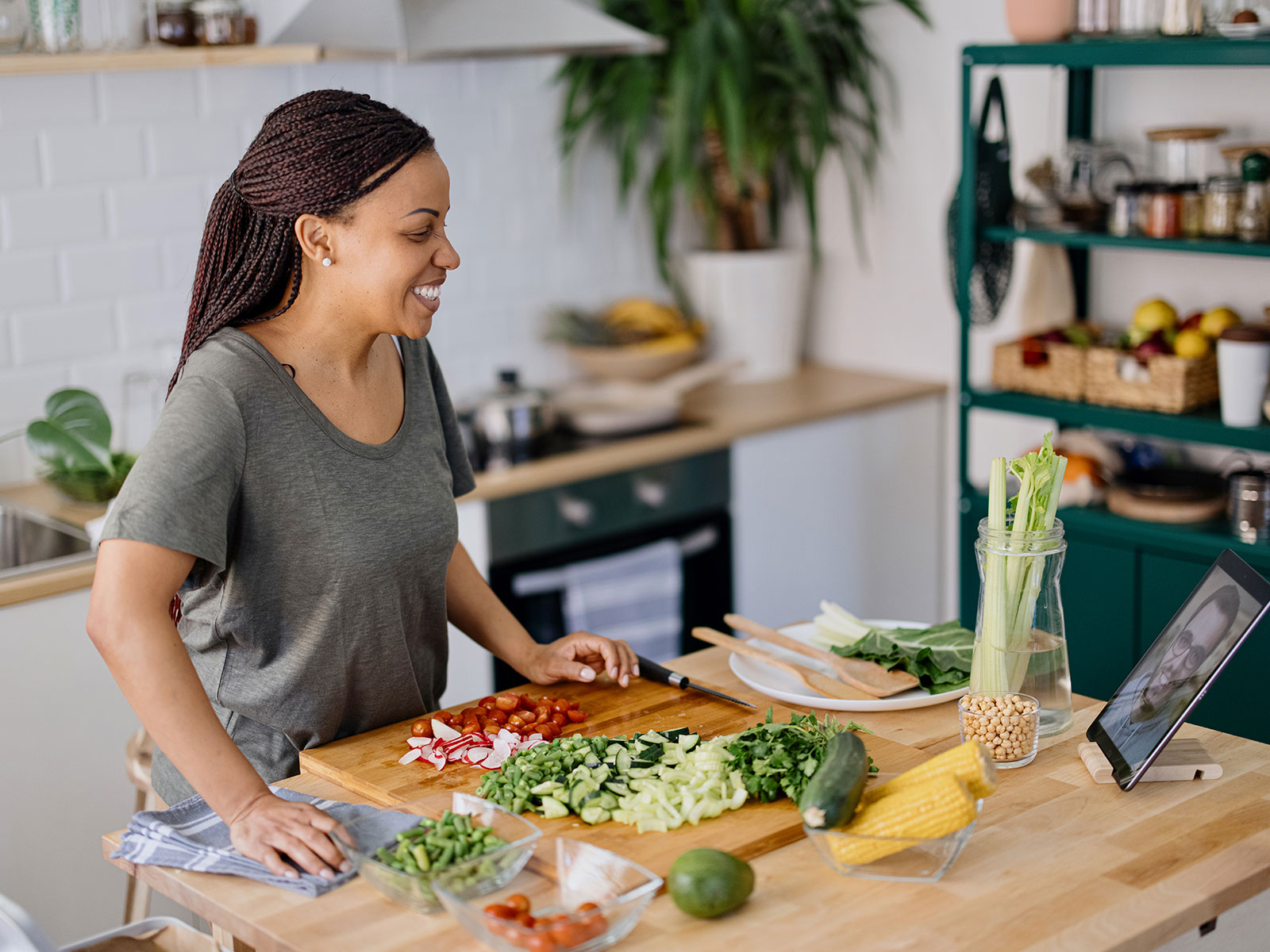 woman smiling while cutting vegetables in her kitchen