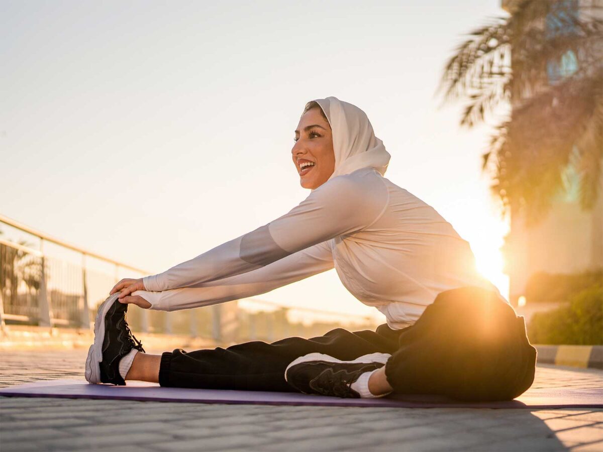 female stretching on a yoga mat outside