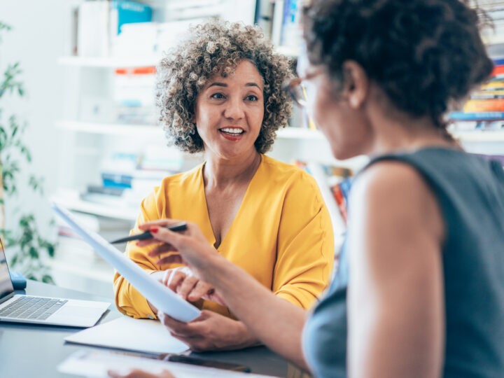 two women collaborate in a workplace setting
