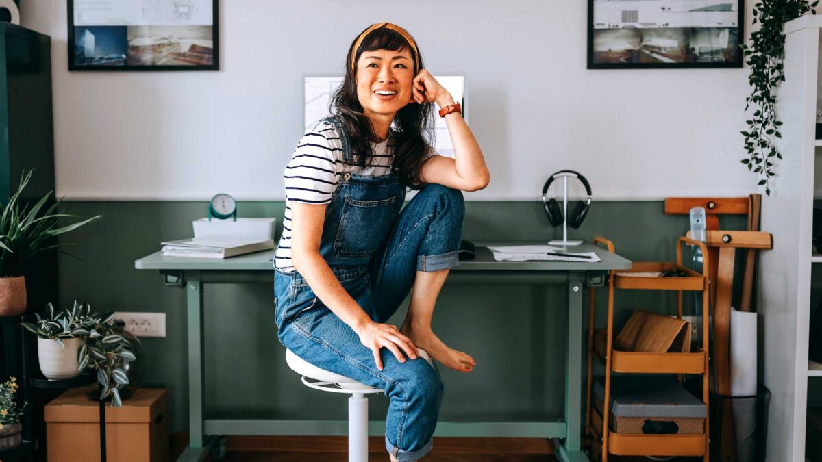 Woman sitting on a stool at her work station smiling
