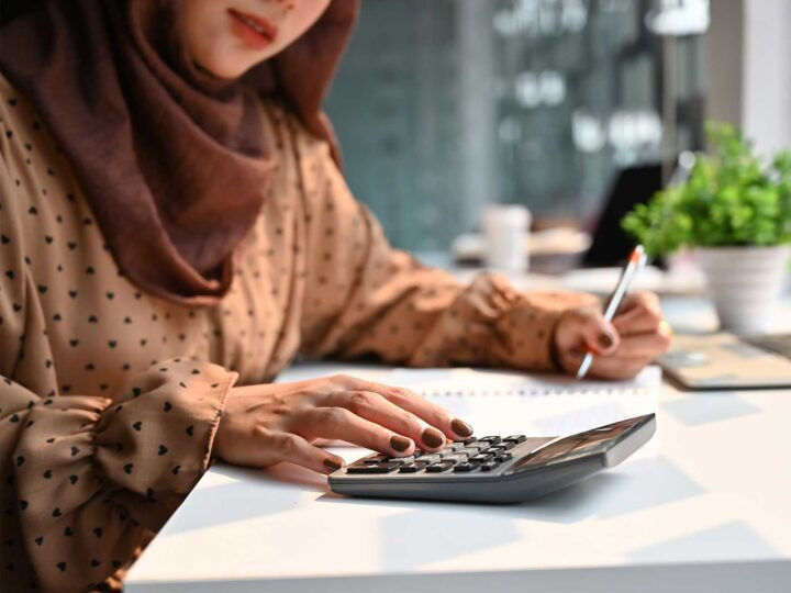 Islam woman working on calculating finances with a calculator
