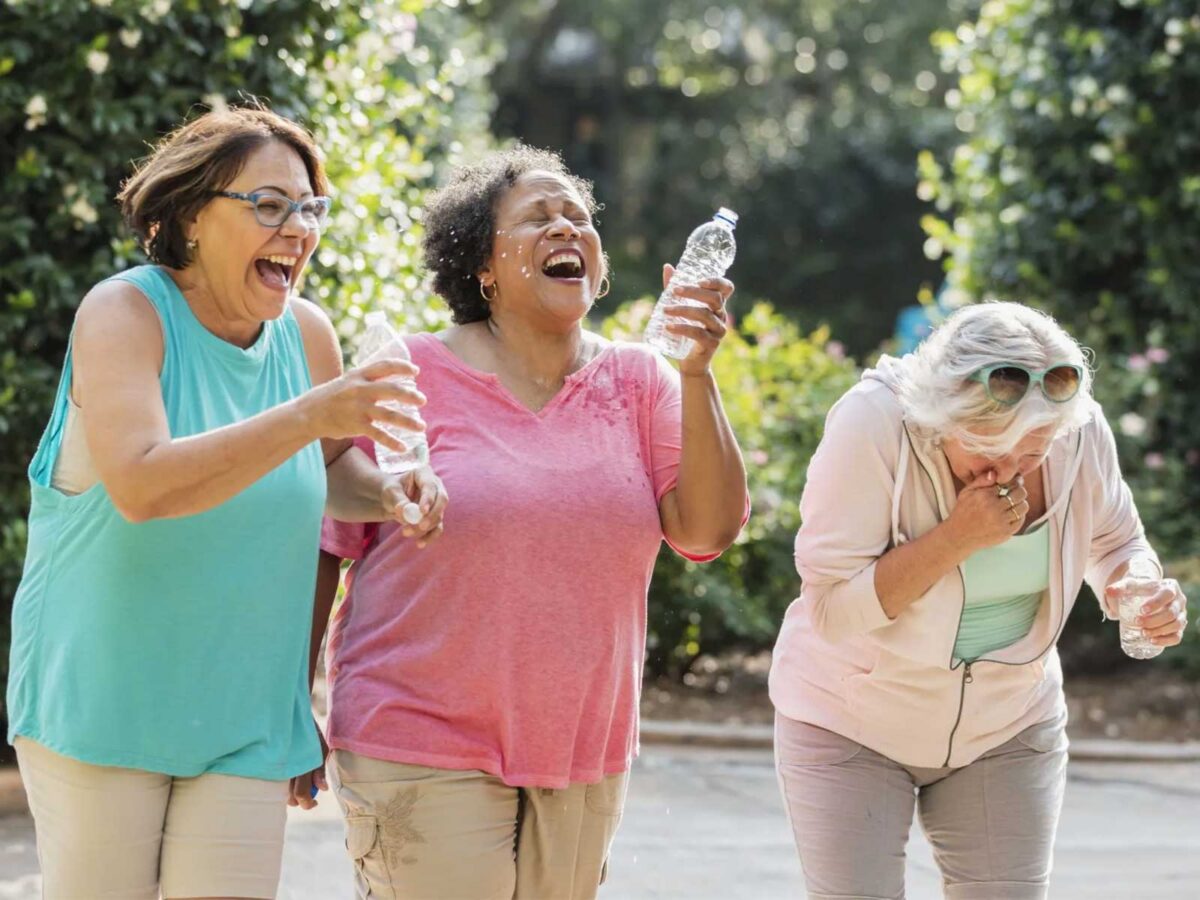 group of three women laughing and spilling water from their water bottles