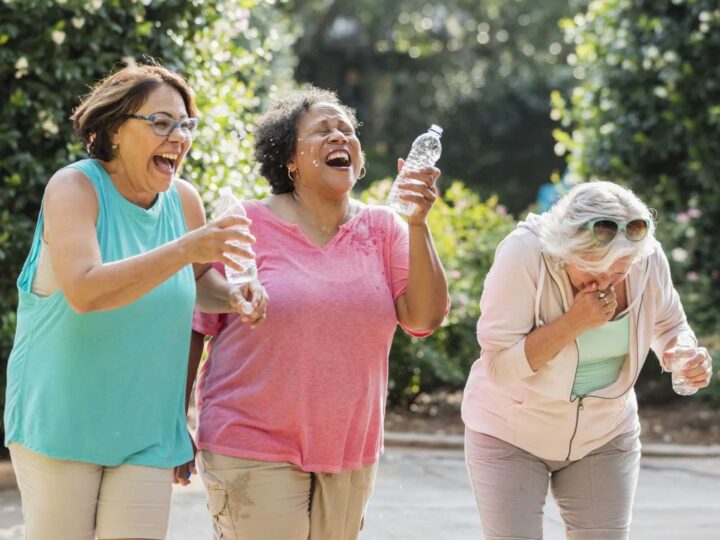 group of three women laughing and spilling water from their water bottles