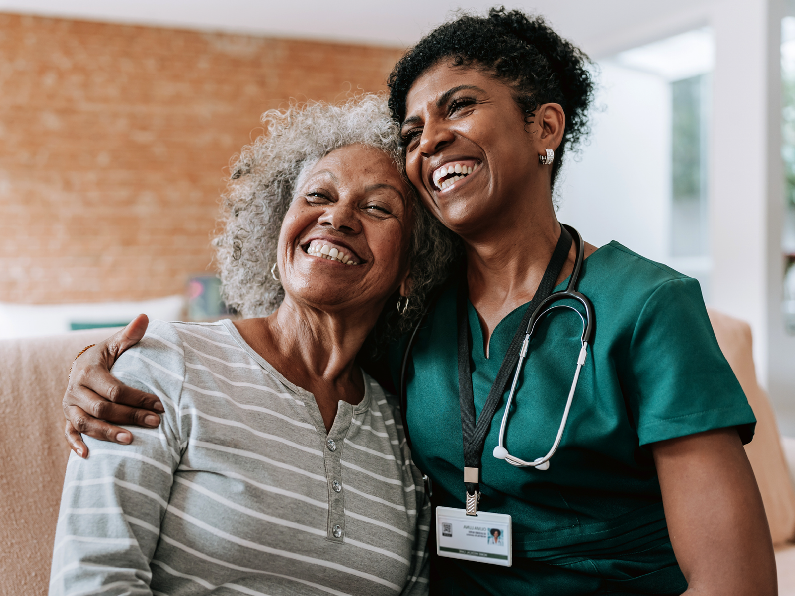 Hospital worker smiling and hugging a patient who is also smiling