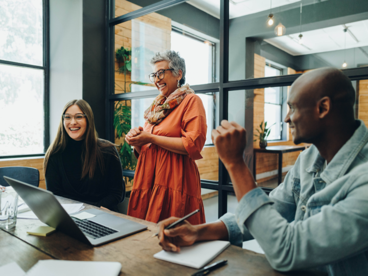 co-workers smiling and talking at a meeting