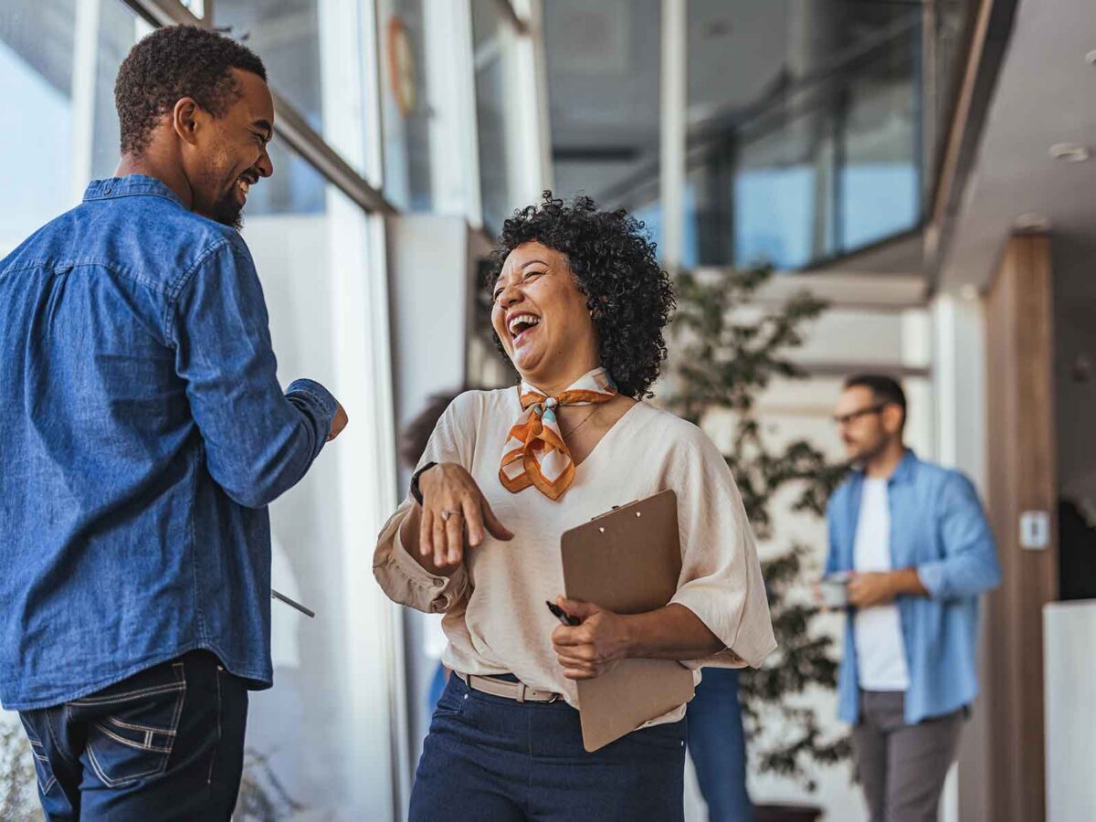 male and female employee smiling and talking to each other at work
