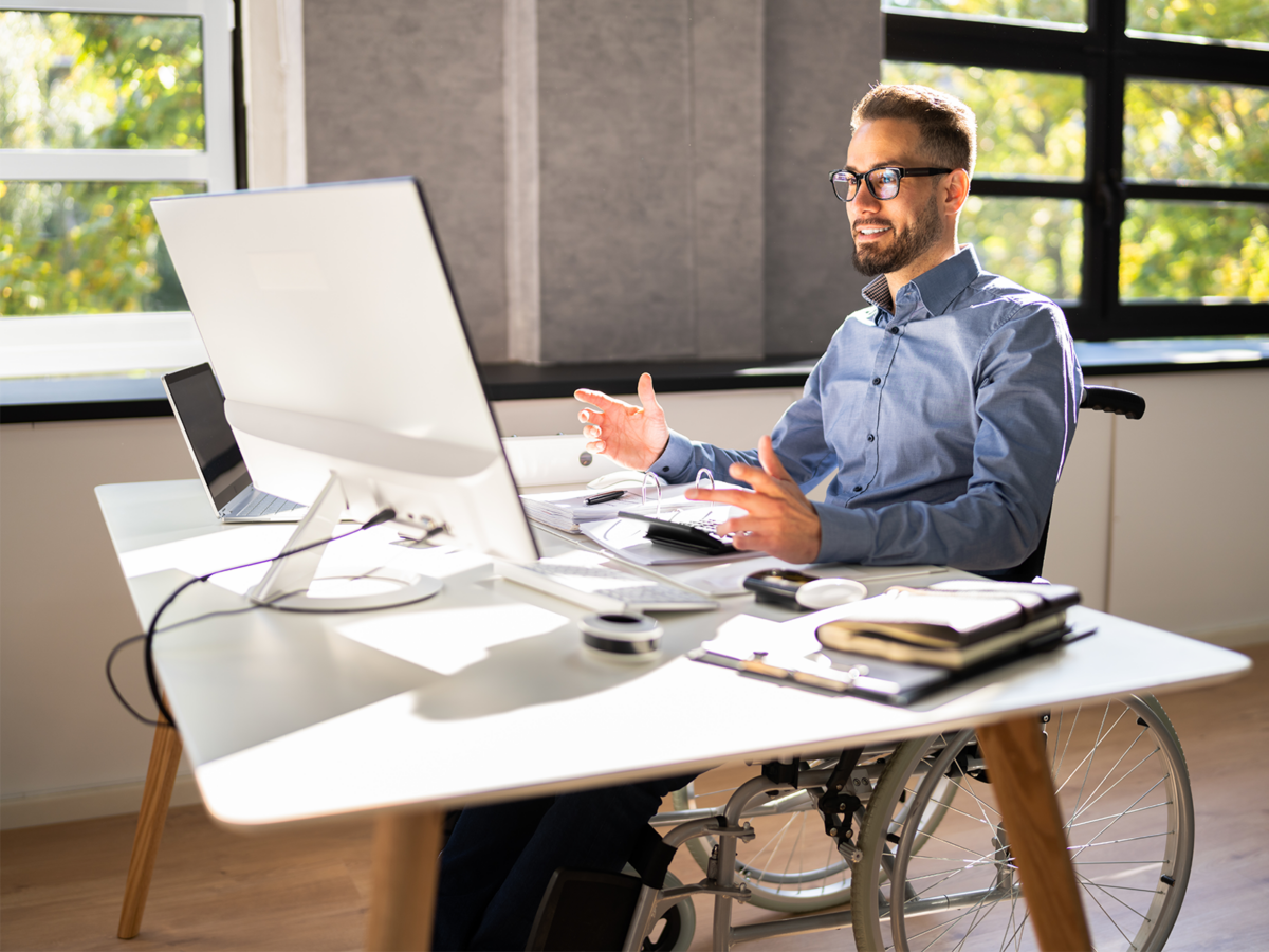 male employee in wheel chair looking at his monitor at his desk