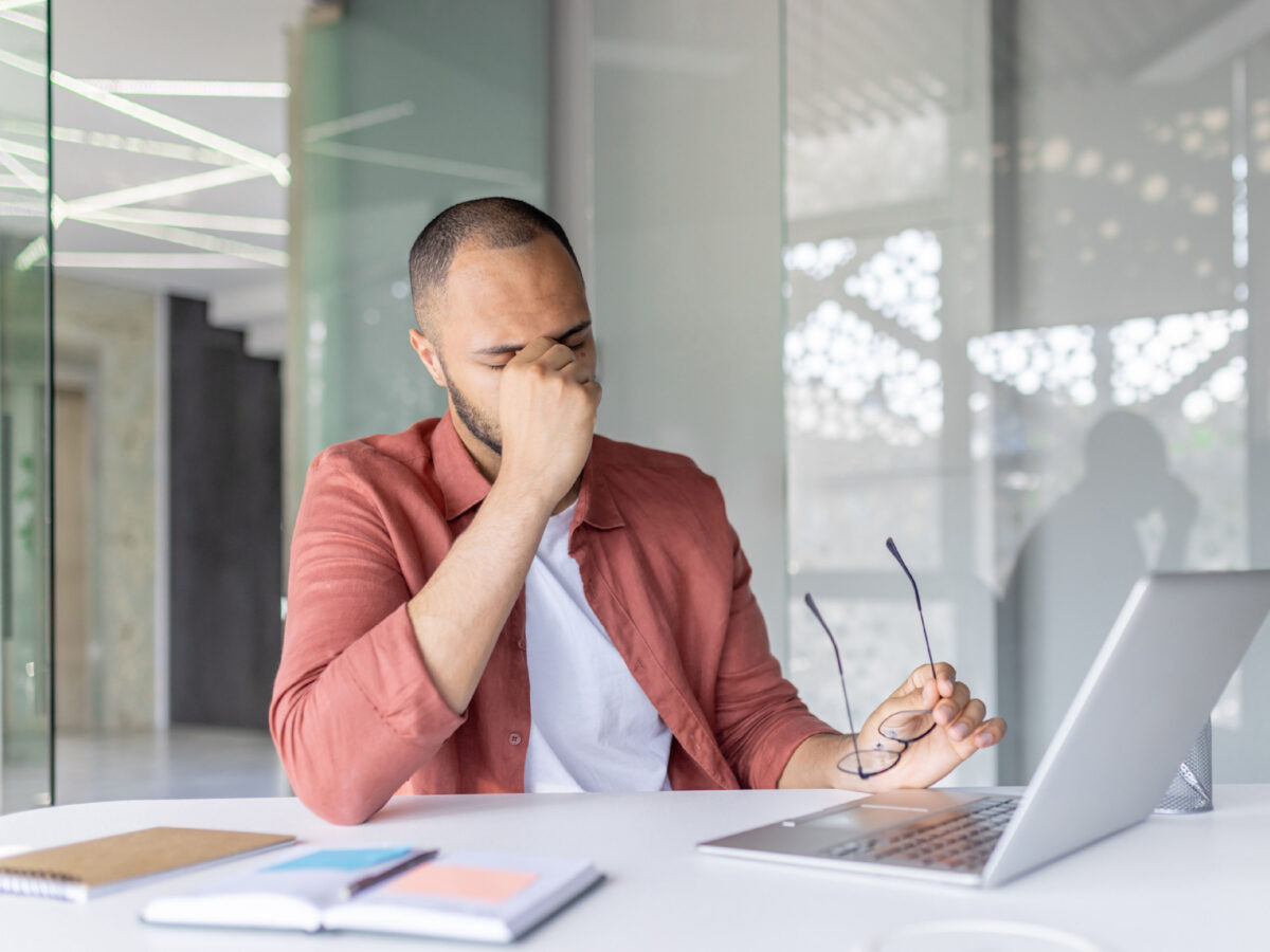 a disengaged employee who is rubbing his eyes after taking off his glasses