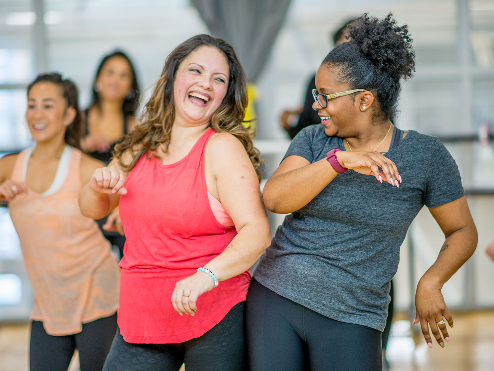 two women smiling while dancing in a workout class