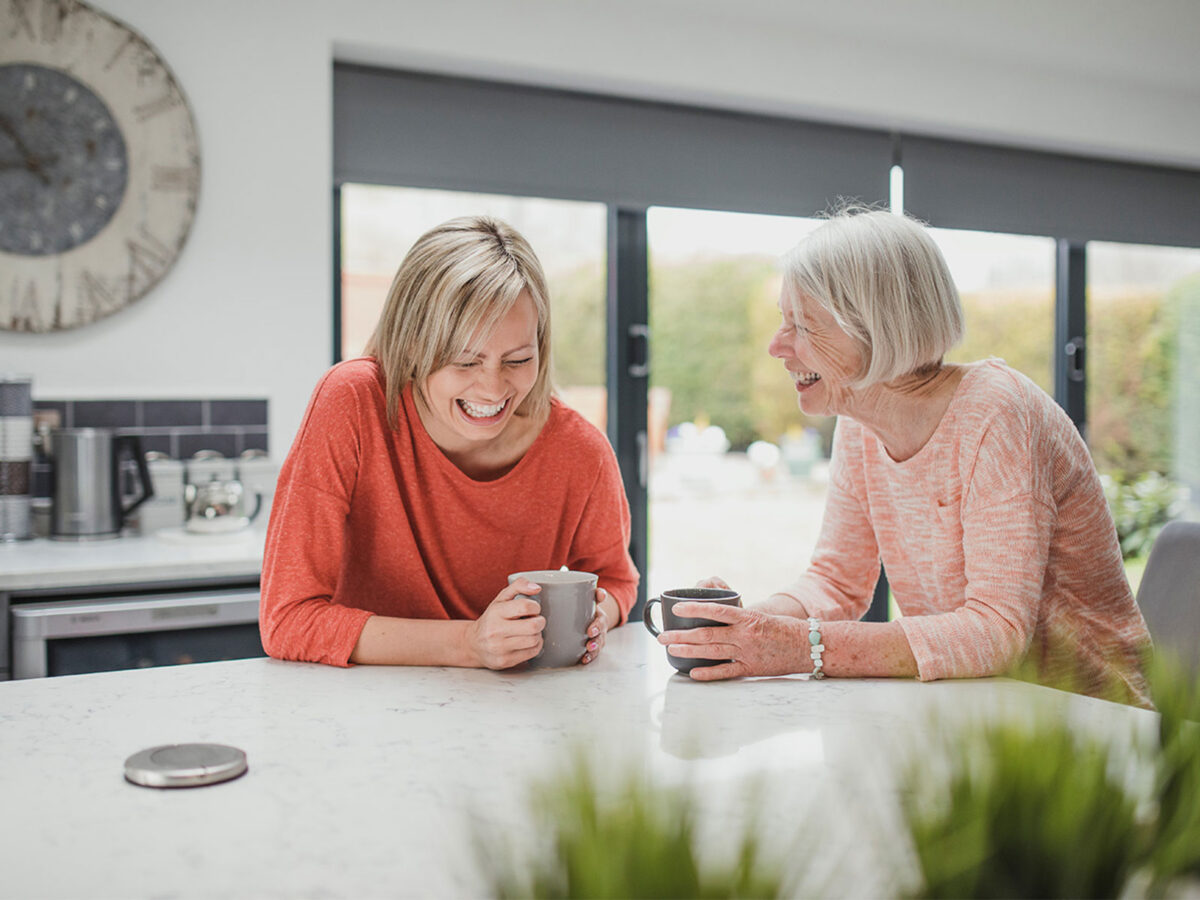 Two HR Leaders smiling in the office while having coffee in the kitchen